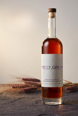 Purple Karma Barley Whiskey bottle with purple barley on a stone surface